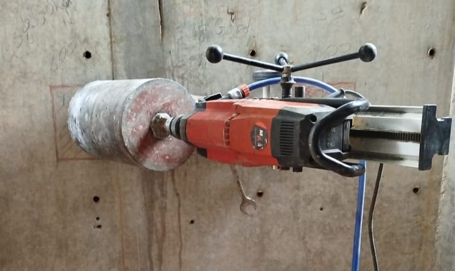 Máquina realizando perfuração em parede de concreto